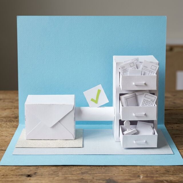 Diorama de papel: un sobre conectado a un archivero con facturas, un libro contable y un sello